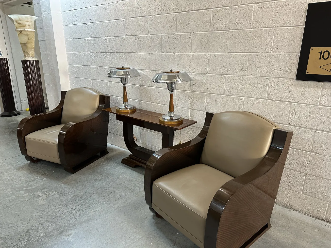 Antique console in a decorative setting with armchairs and lamps.