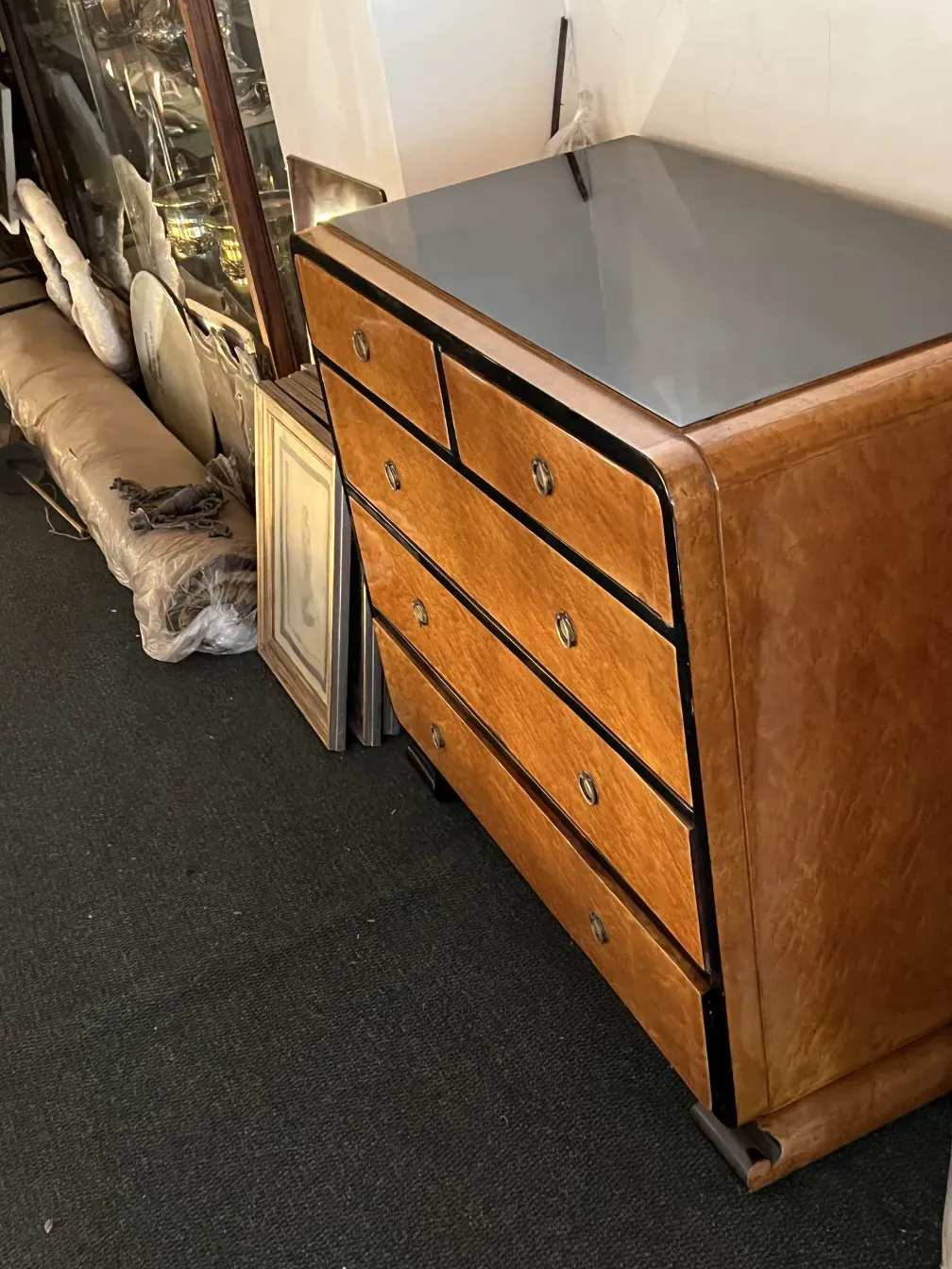 Antike Schublade mit ornamentalen Details und glänzenden Griffen, in einem Umfeld mit anderen Dekorationsgegenständen.