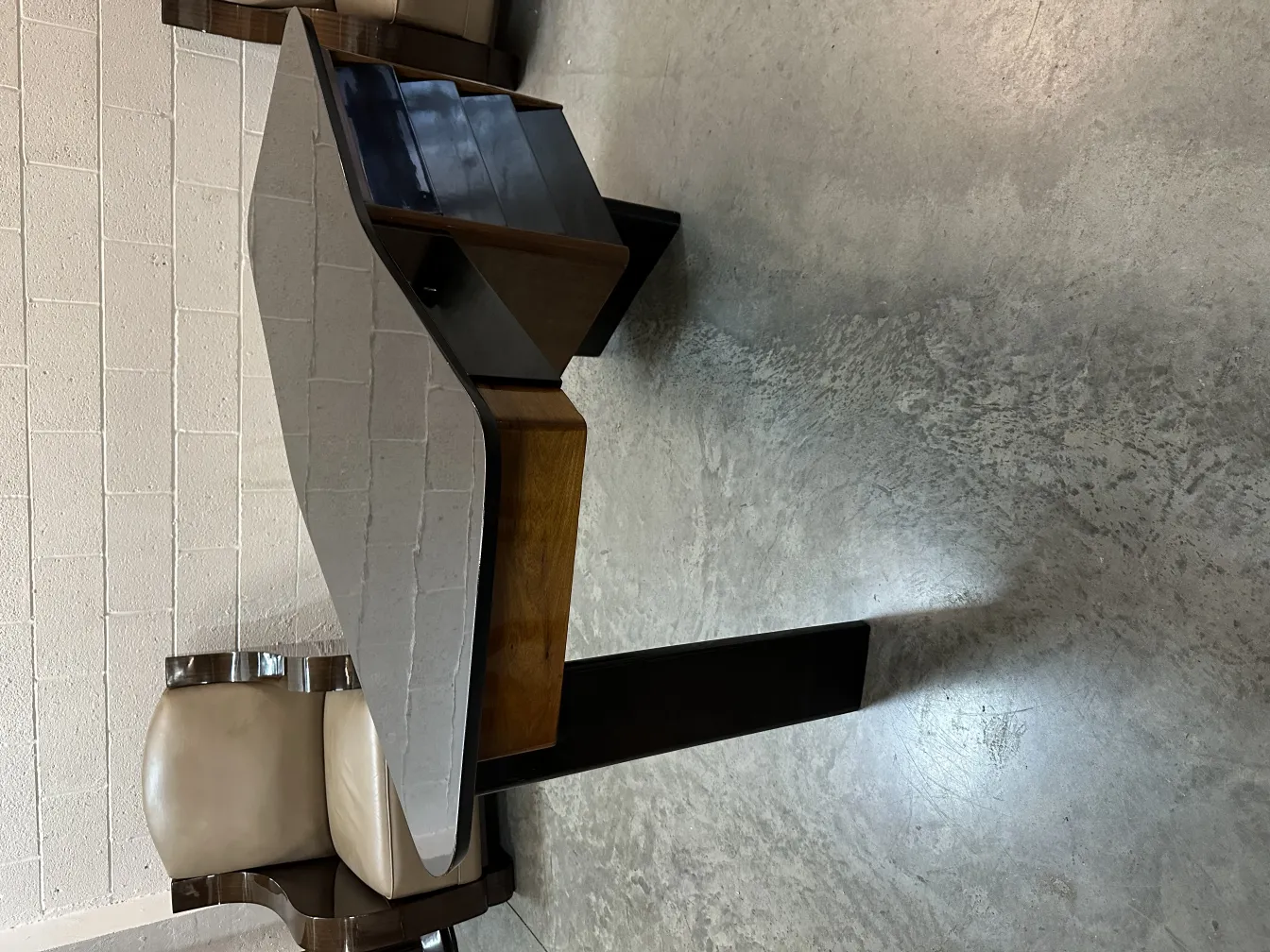 escritorio antiguo con forma única y estanteria lateral, en un ambiente minimalista.