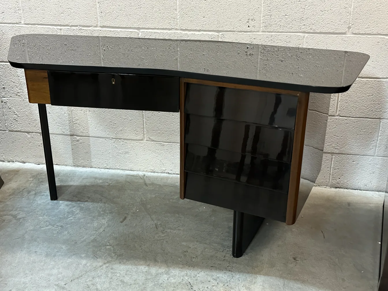 Antiker Schreibtisch mit schwarzen Oberfläche und elegantem Design. Beinhaltet eine Schublade und seitlichen Stauraum.