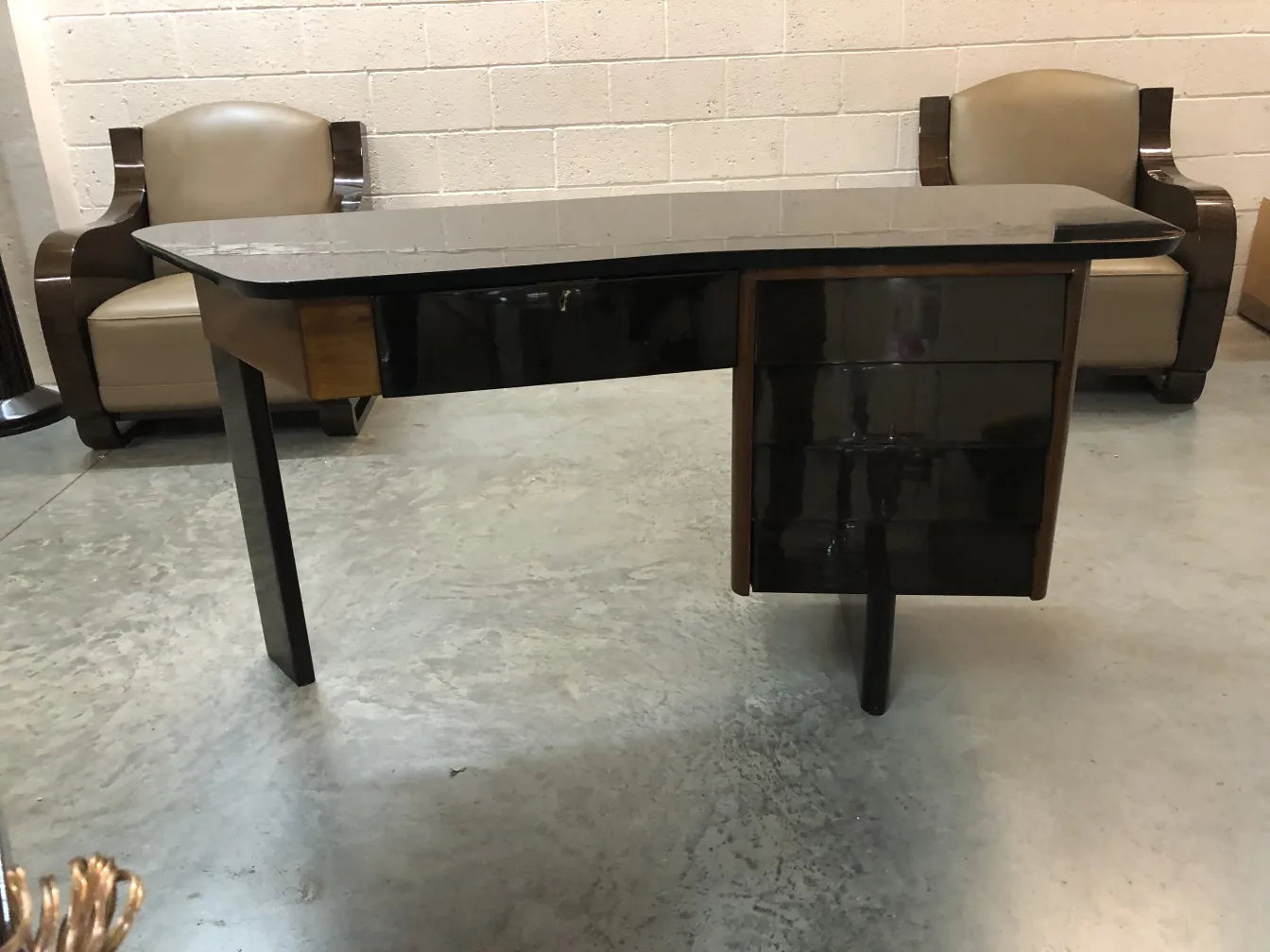 antique desk with a curved design and two drawers, in a minimalist setting.