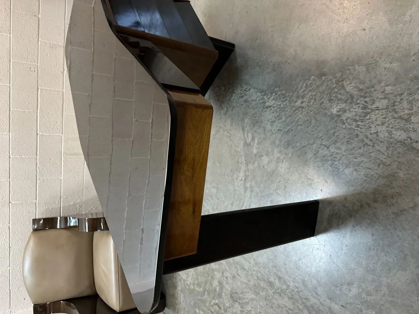 Antique desk with a unique curved design and elegant finishes, next to a chair with light upholstery.