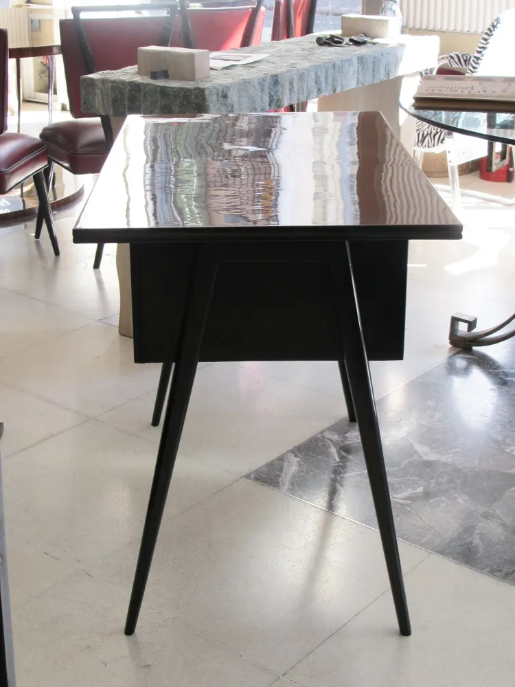 Antiker Schreibtisch mit schlanken Beinen und simplem Design in heller Umgebung.