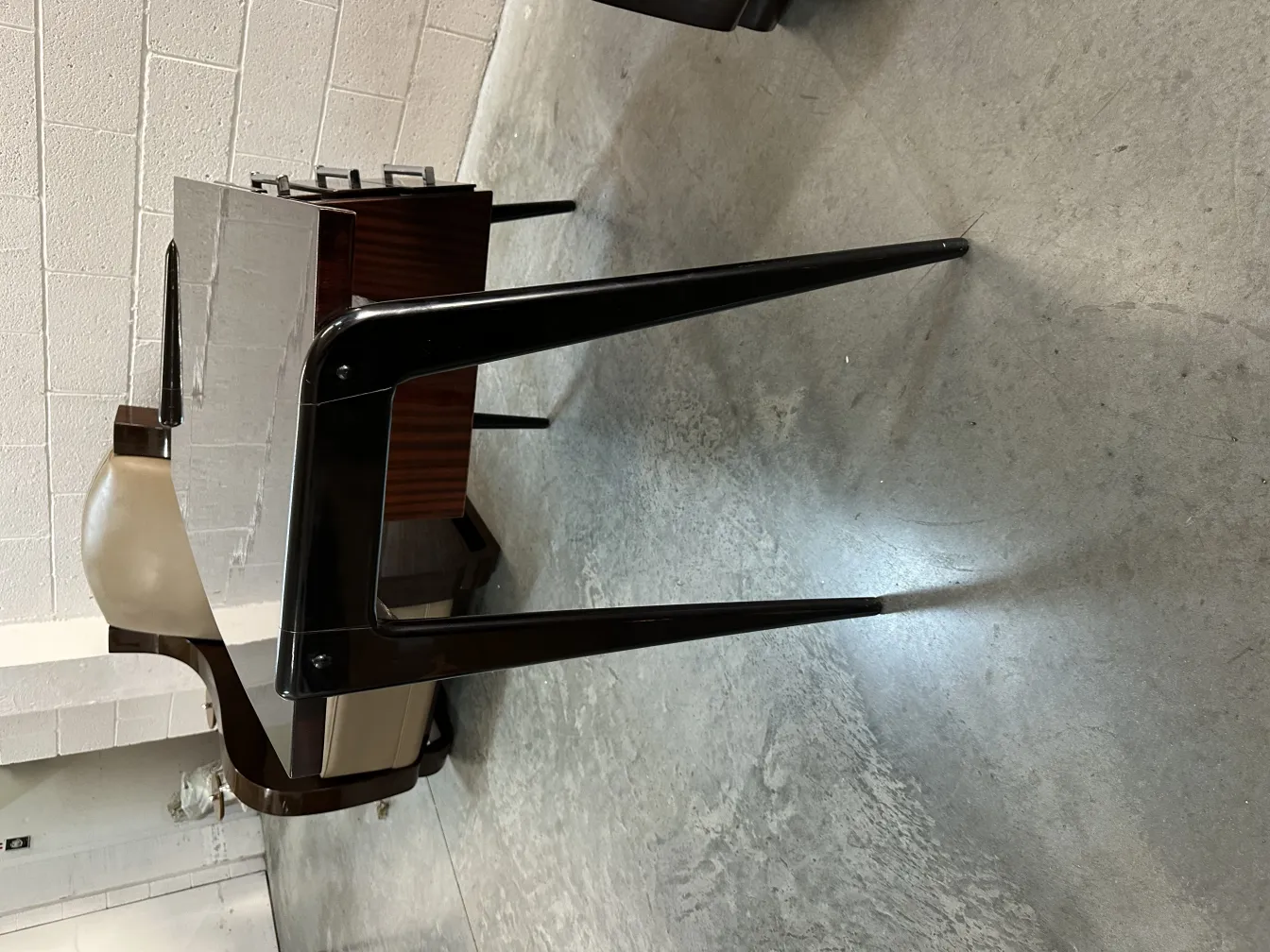 Antique desk with shiny finish and thin legs, in a minimalist environment.