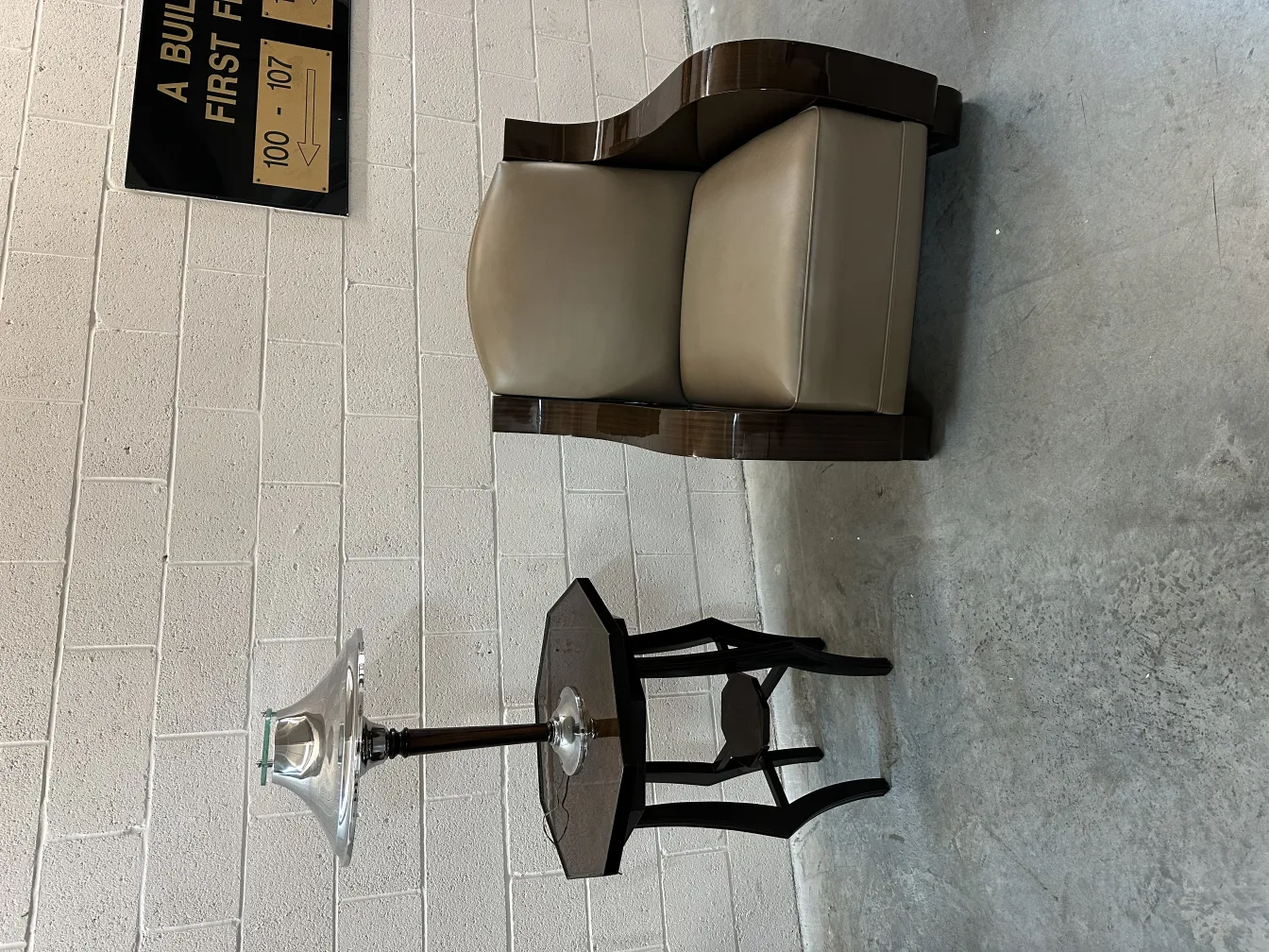 ancienne lampe de bureau avec une base en verre brillant et un design élégant, accompagnée d'un fauteuil contemporain en arrière-plan