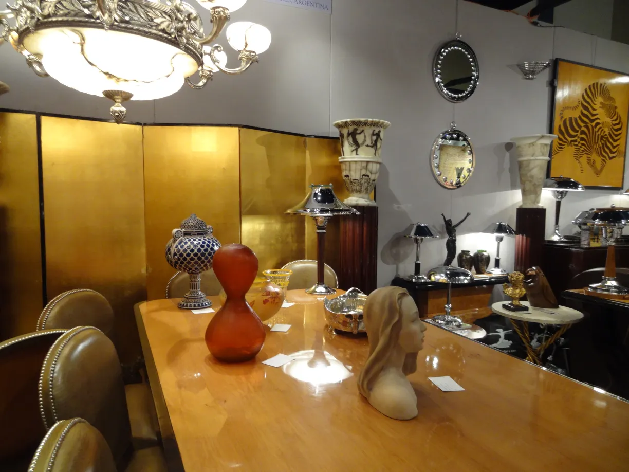 Lampada da tavolo antica con base e paralume decorativi, circondata da altri oggetti in un ambiente elegante.