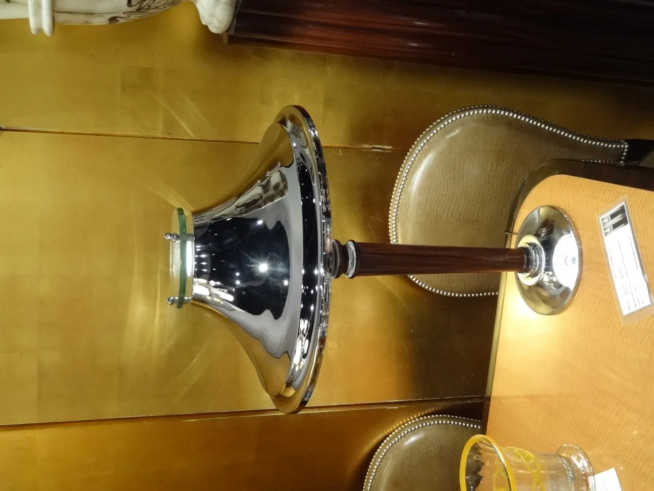 Lampe de bureau ancienne avec base brillante et détails élégants. Fond doré et ambiance classique.