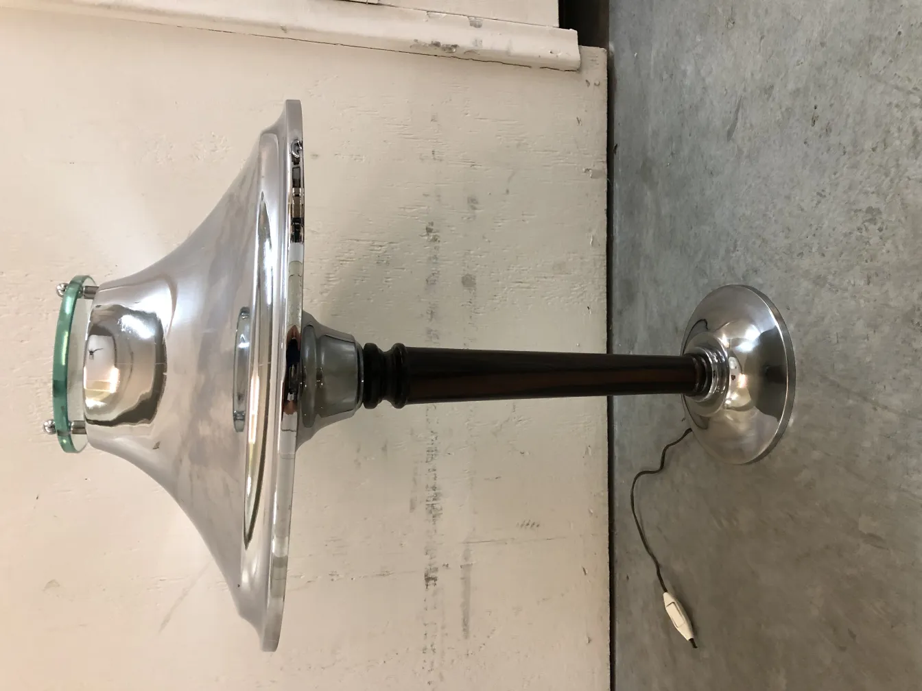 Lampada da tavolo antica con finitura lucida in un ambiente neutro.