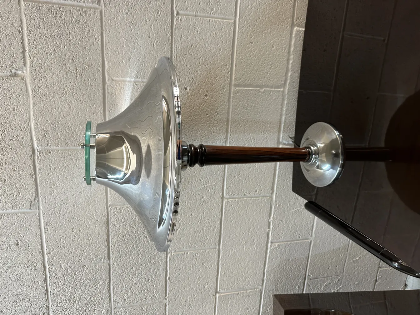 Antique table lamp with shiny metal base and reflective shade, set in an elegant environment.