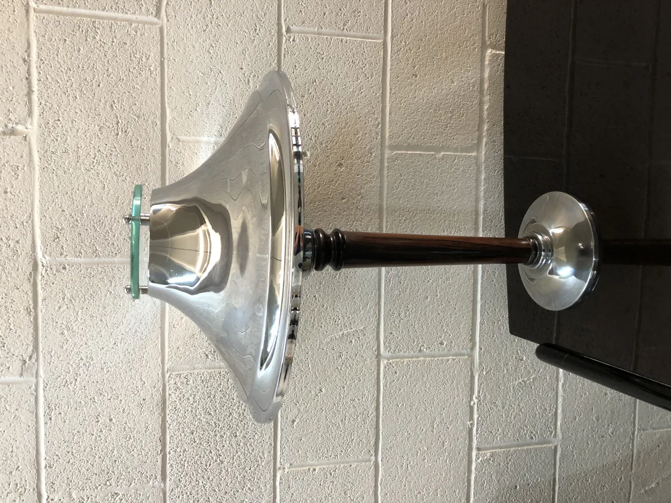 Antike Tischlampe mit glänzendem Fuß und einzigartiger Form, neutraler Hintergrund.