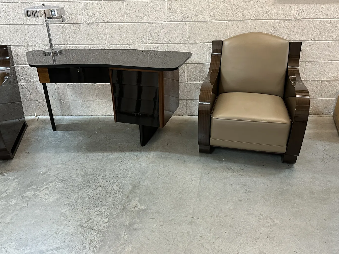 Antigua lámpara de mesa para escritorio moderna con base plateada, junto a una silla suave.