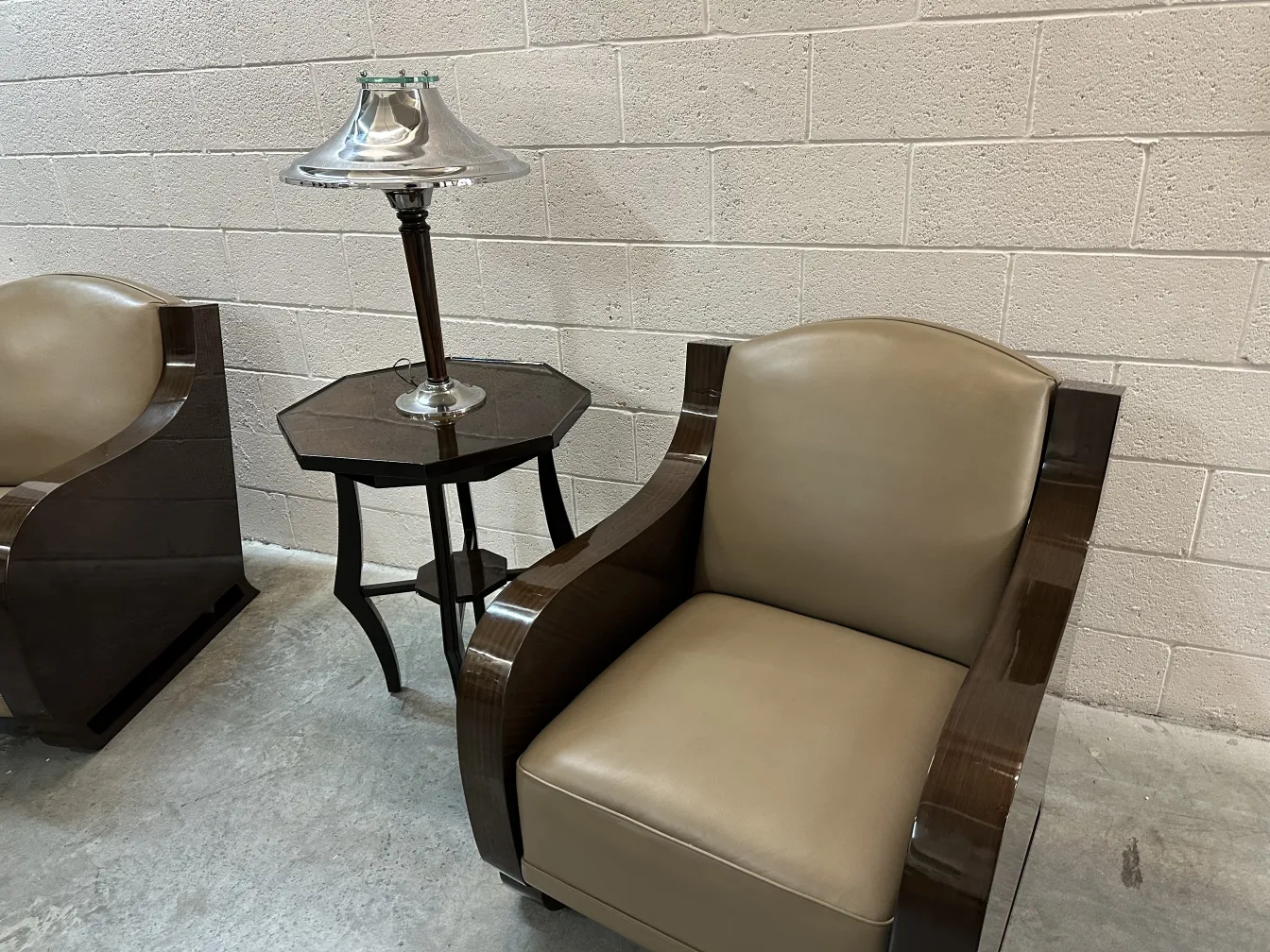 Luminária de mesa antiga com tela em forma de sino e base elegante, ao lado de poltronas claras