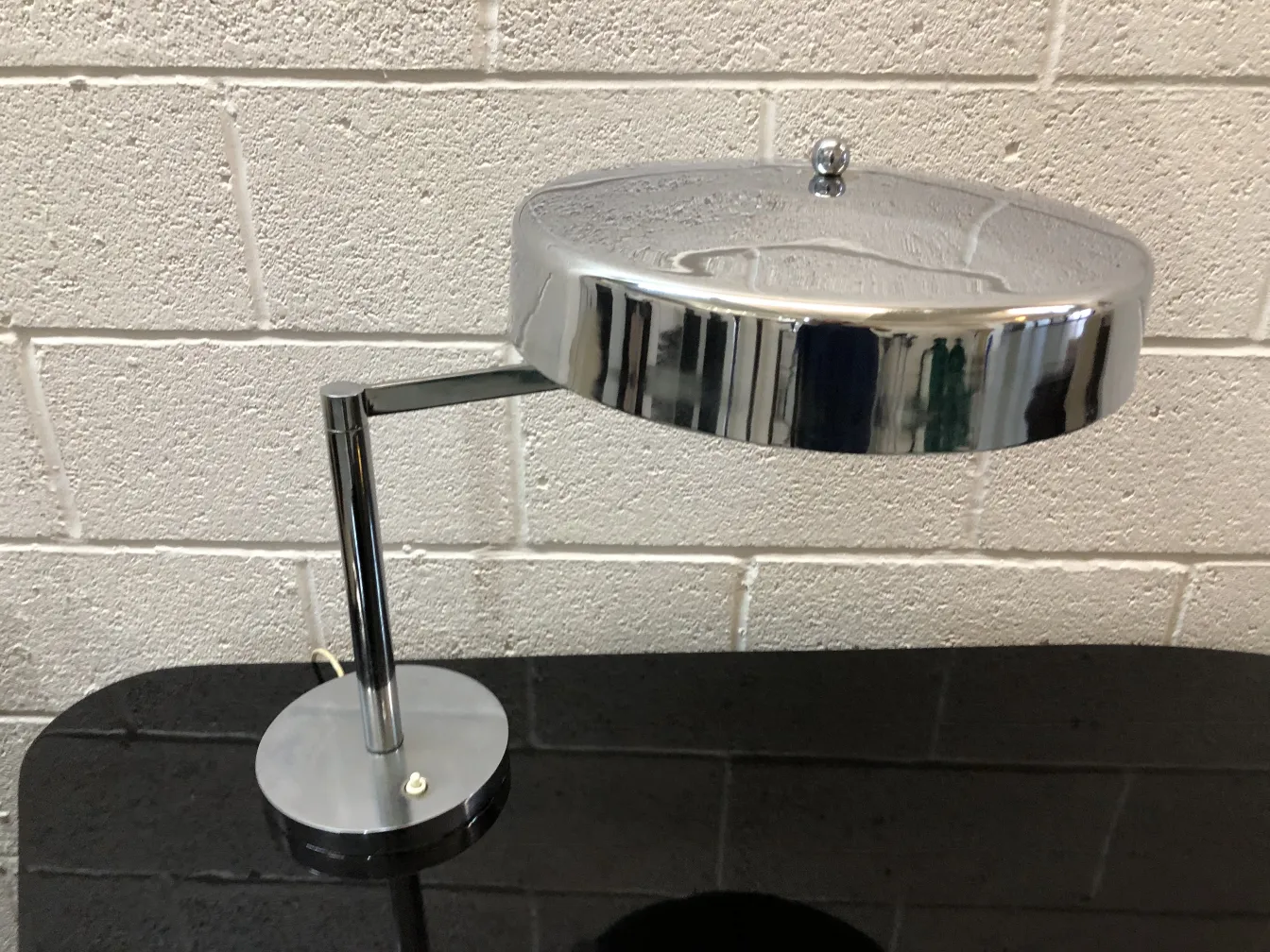 antique table lamp with a shiny design, circular base and adjustable arm