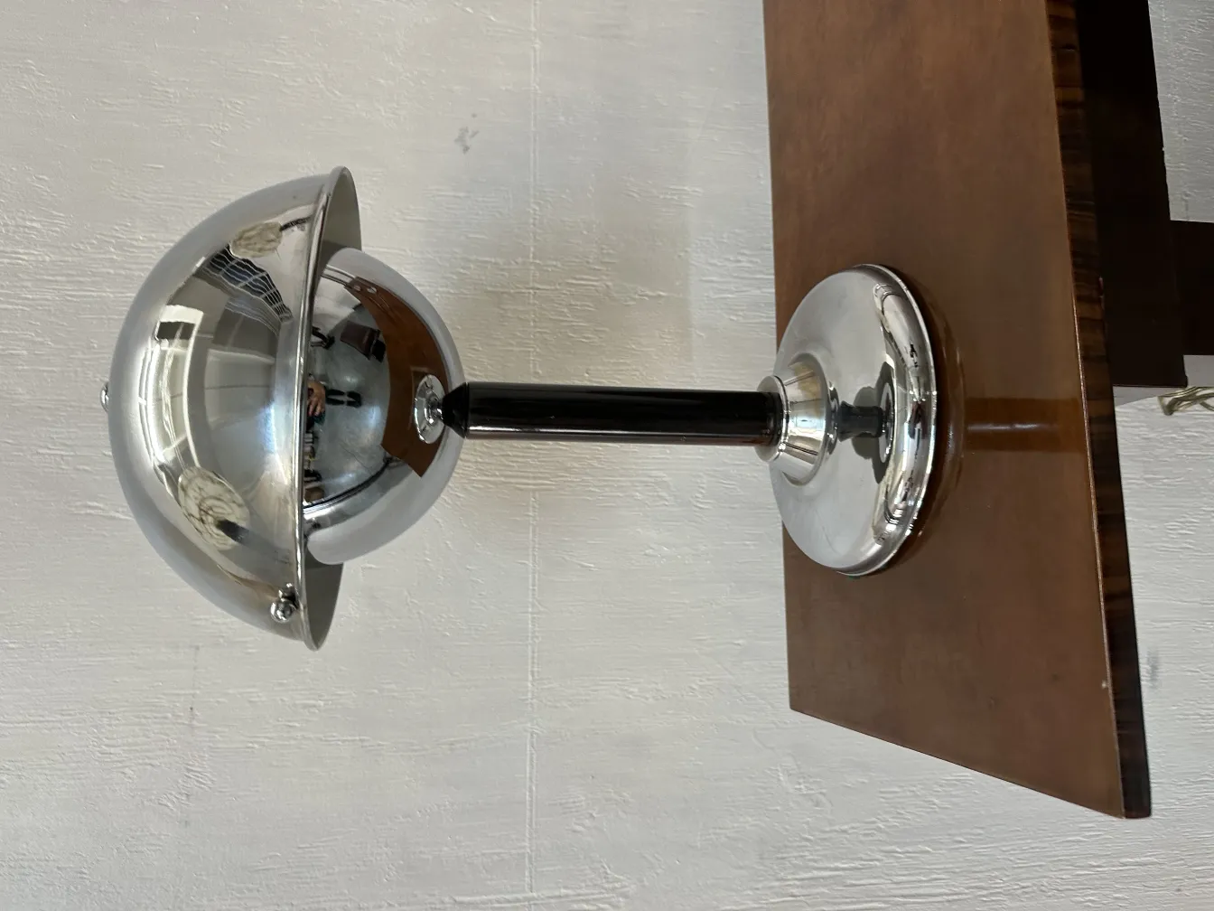 Lampada da tavolo antica con design sferico lucido e elegante supporto nero, posizionata su un tavolo di legno.