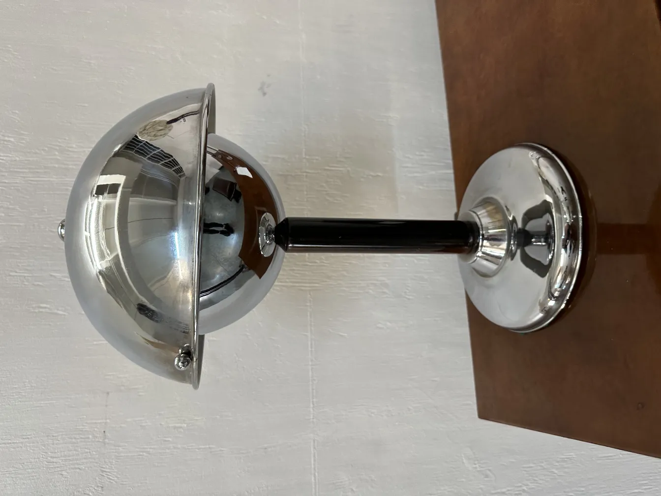 Lámpara de mesa antigua con diseño reflectante en un fondo neutro.