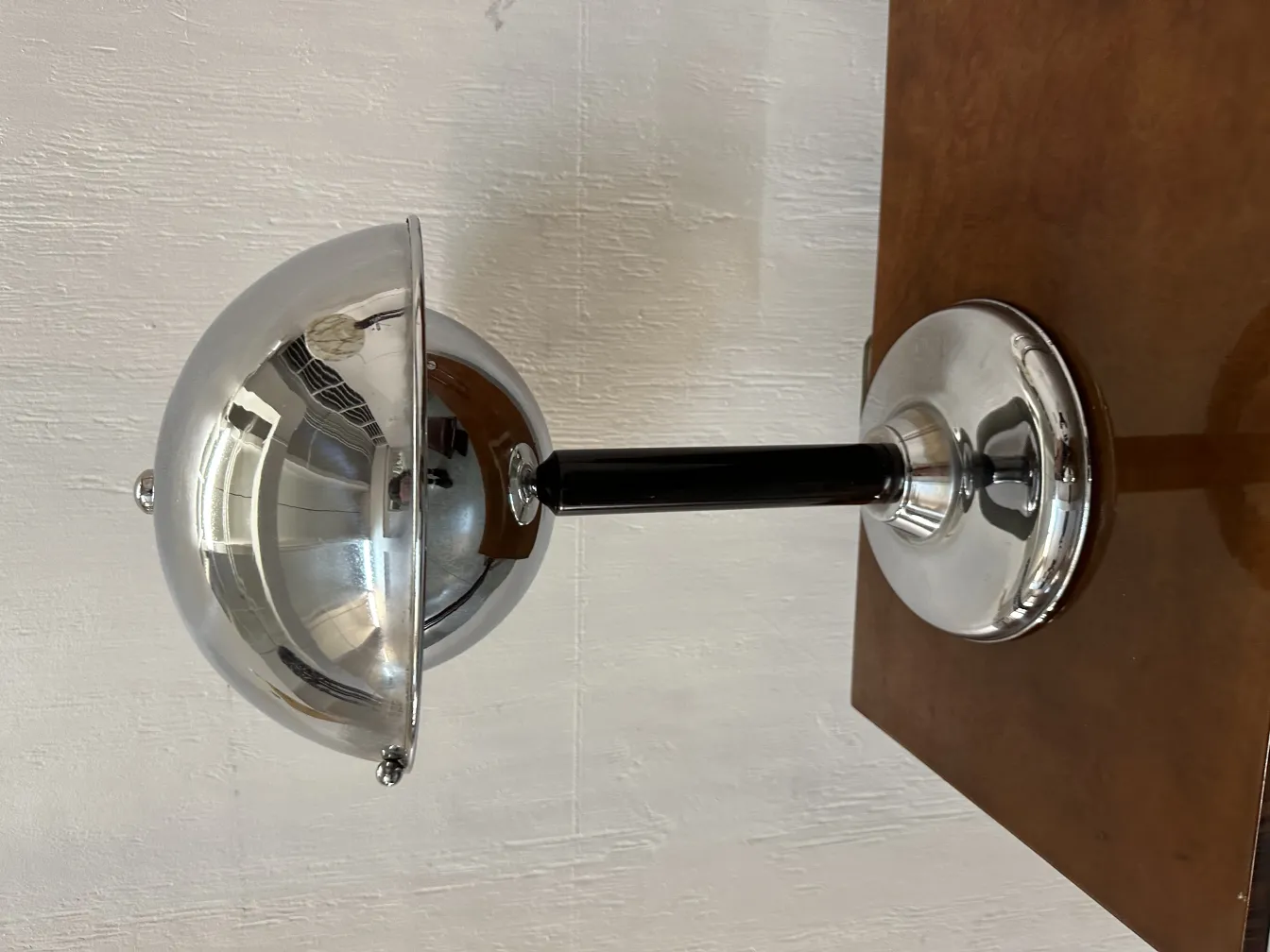 Lampada da tavolo antica con luce brillante e paralume inclinato su un tavolo di legno.