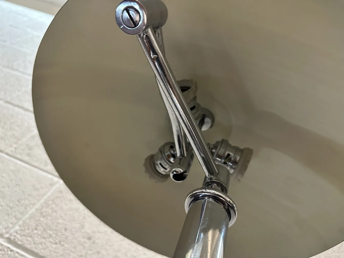 Alte Tischlampe mit glänzendem Fuß und sanften Details in einer beleuchteten Umgebung.