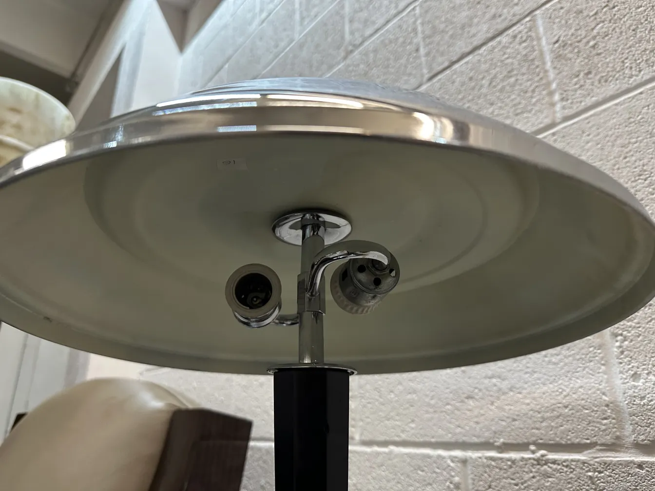 Unteransicht einer antiken Tischlampe mit glänzendem Schirm und freiliegenden Glühbirnen