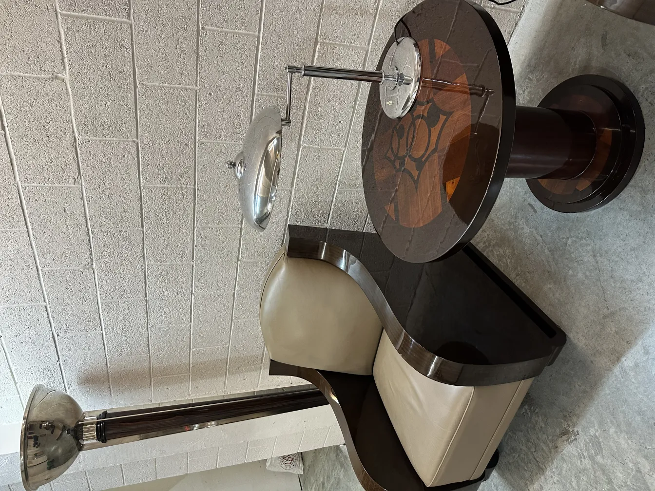 lampada da tavolo antica con base minimale e luce soffusa, accanto a una poltrona curva