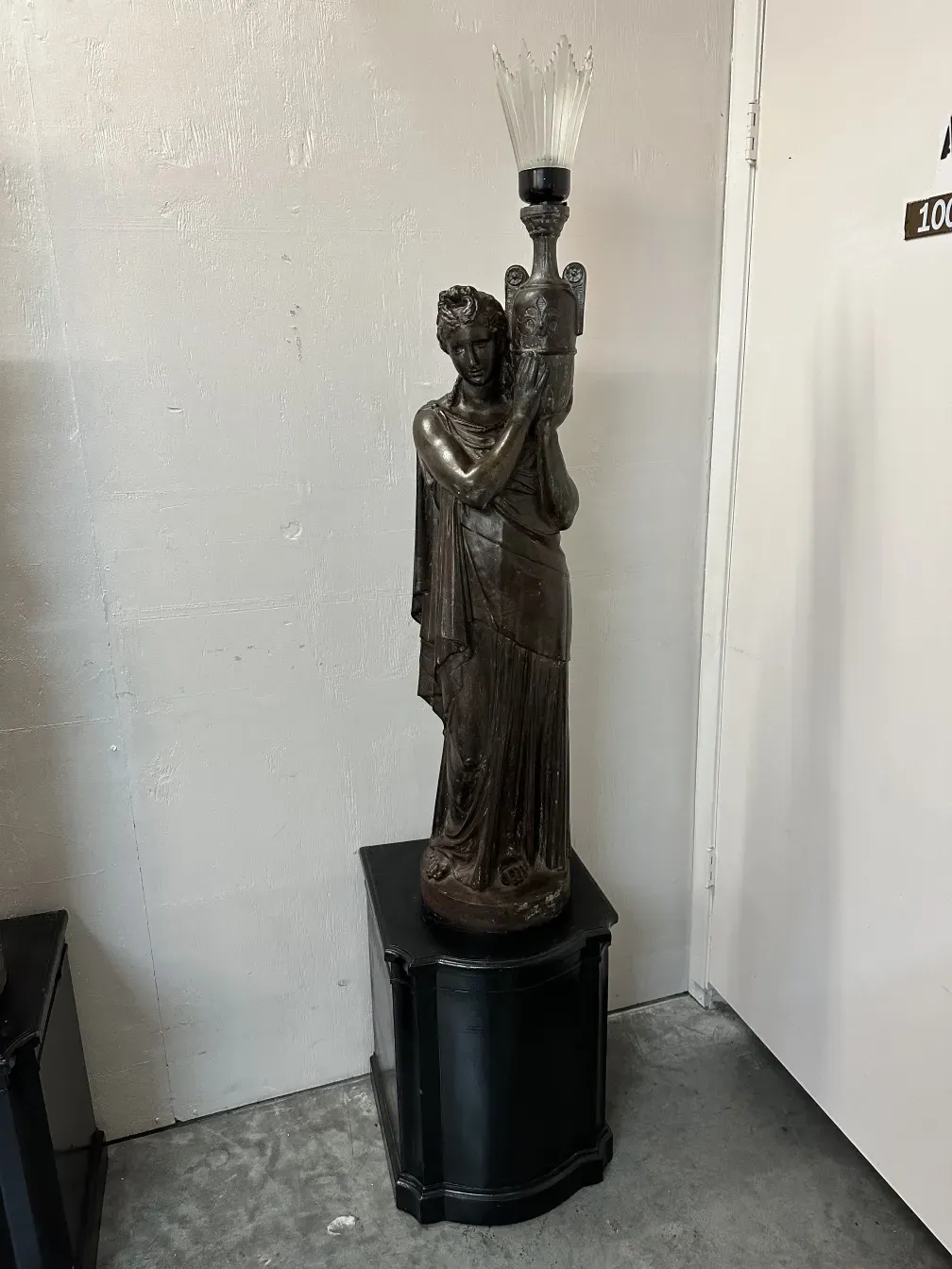 Duas lâmpadas de piso antigas com figura decorativa em ambiente neutro.