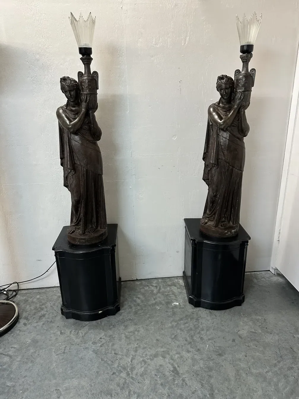 Tra le antichità, ci sono due lampade da terra decorative con finitura scura e dettagli scultorei.