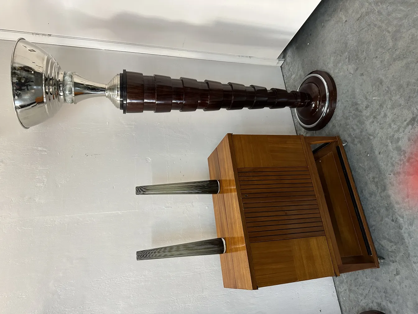 Two antique floor lamps next to a wooden furniture piece