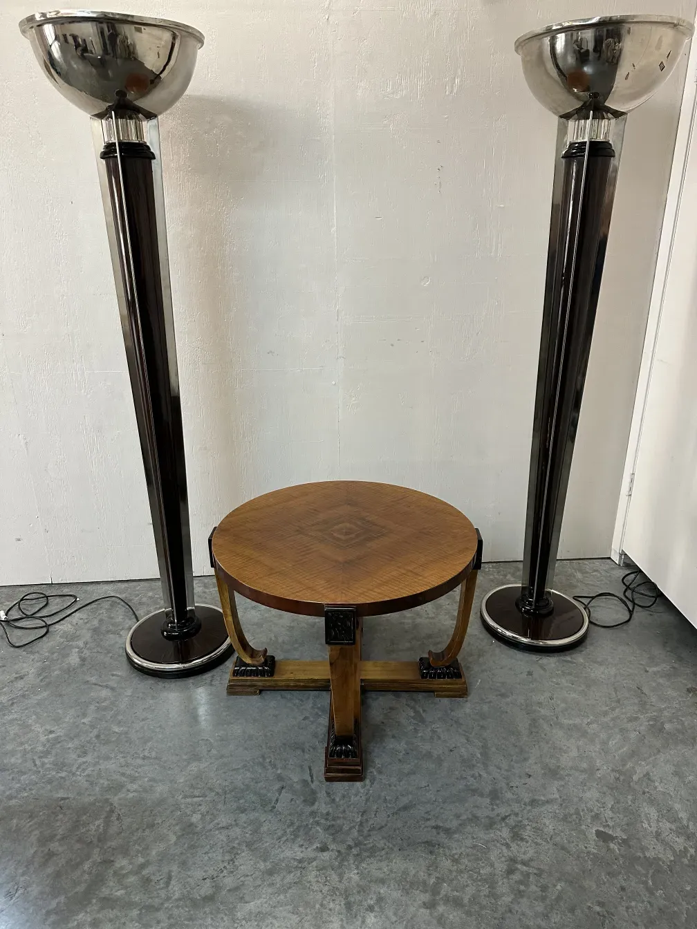 Two antique armchairs in a contemporary setting. Lamps and a round table are visible.