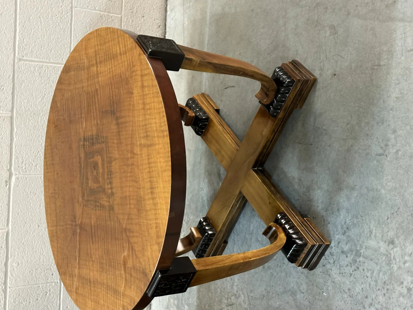 Antique round coffee table with X-shaped base, simple background.