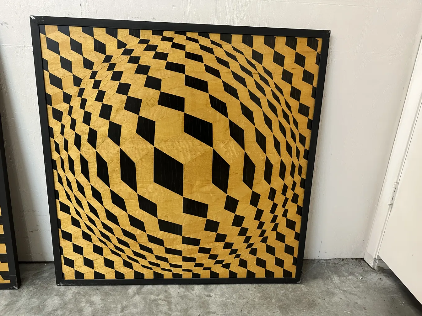 Marqueterie décorative ancienne avec un motif géométrique en teintes dorées et noires.