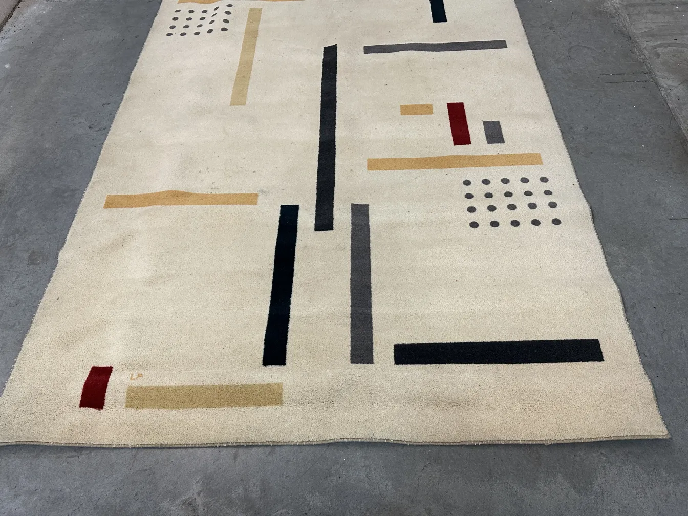 Antiker Teppich mit bunten geometrischen Mustern und hellem Hintergrund.