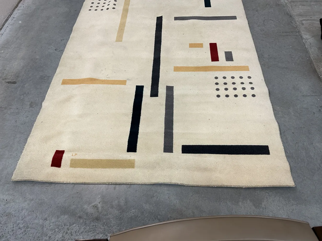 Alfombra antigua con diseños geométricos en tonos beige y negro, estilo abstracto.