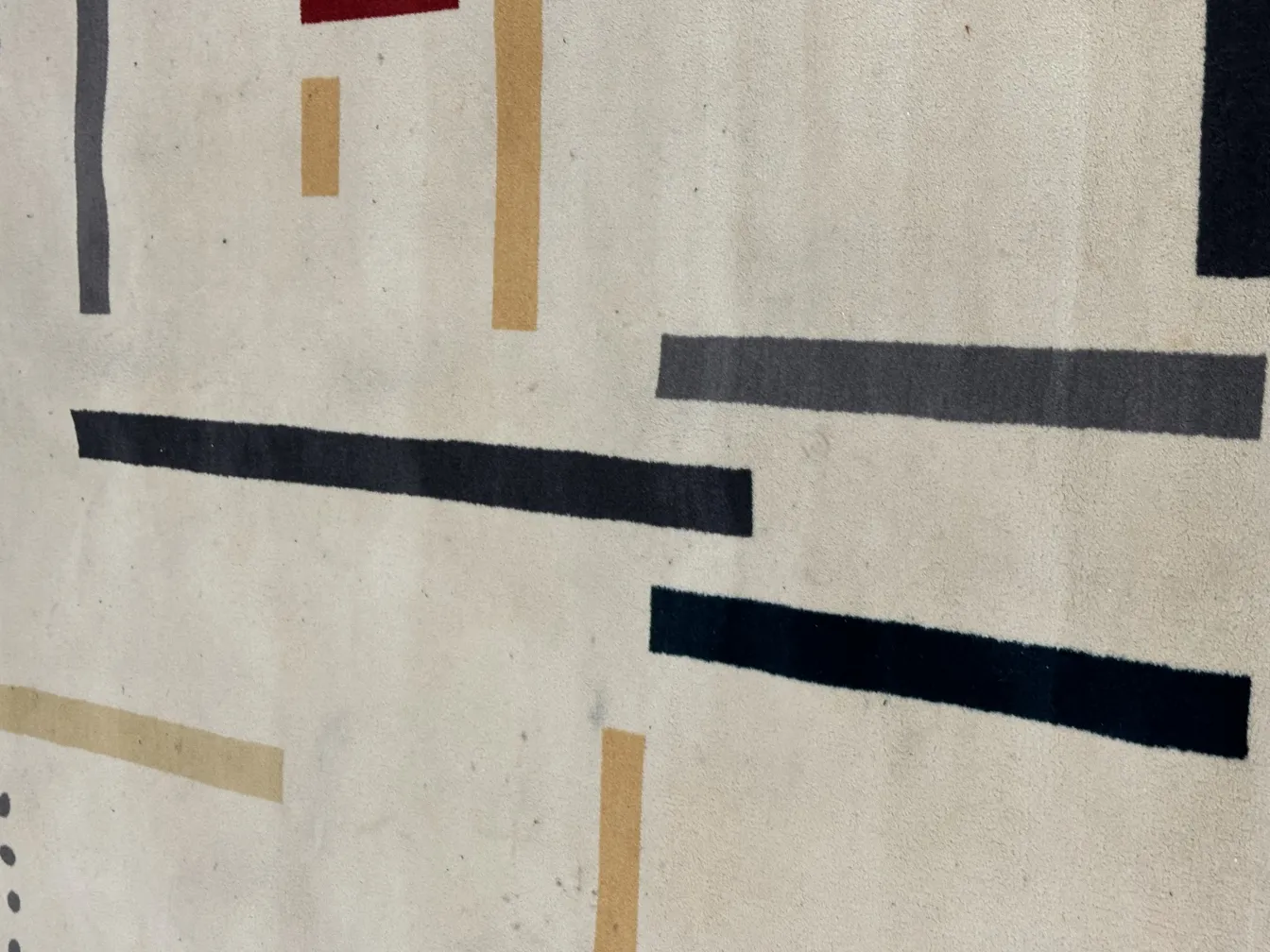 Antique carpet featuring geometric patterns in light and dark shades.