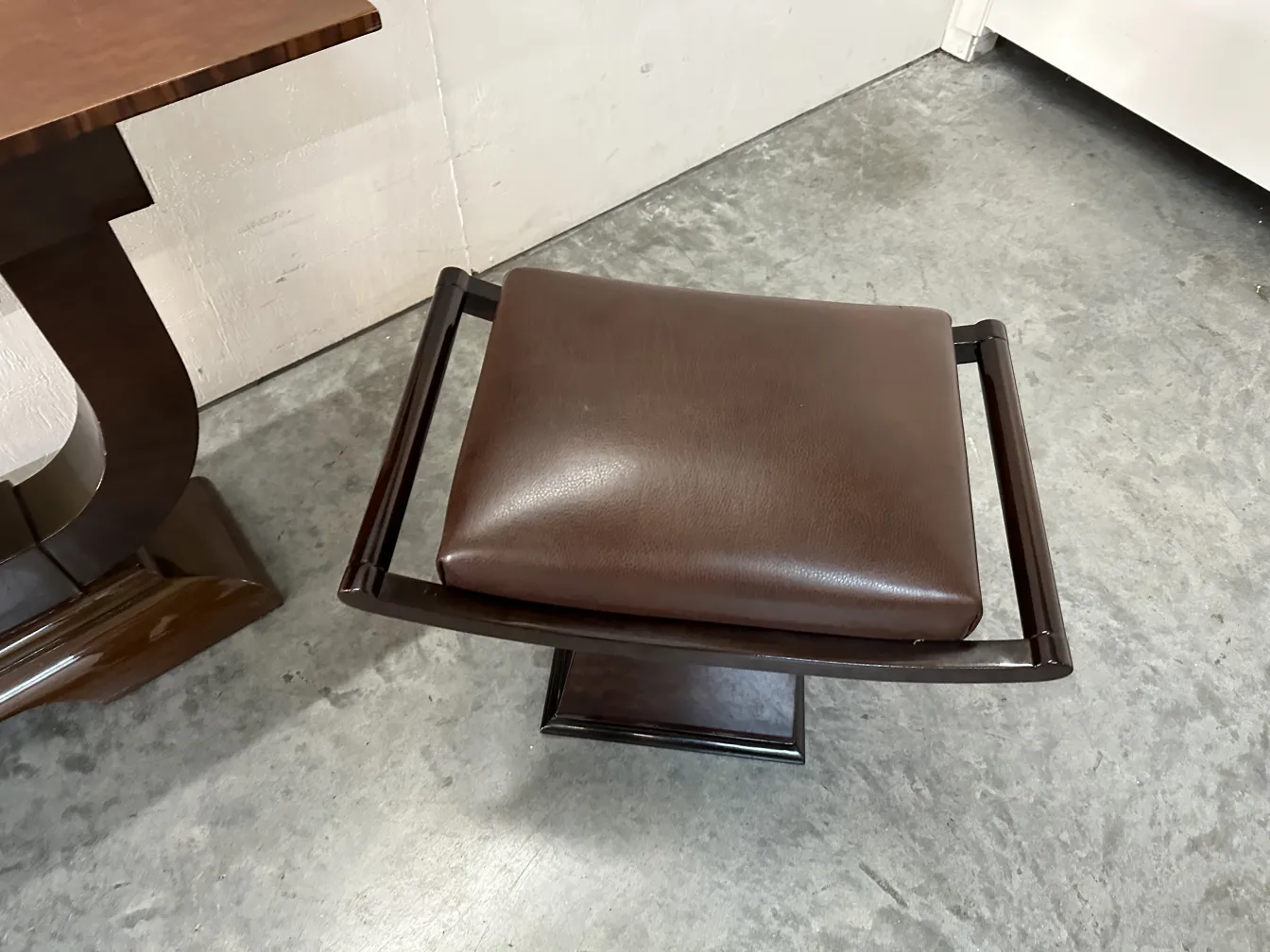 banqueta antiga com assento acolchoado e base sólida em ambiente contemporâneo