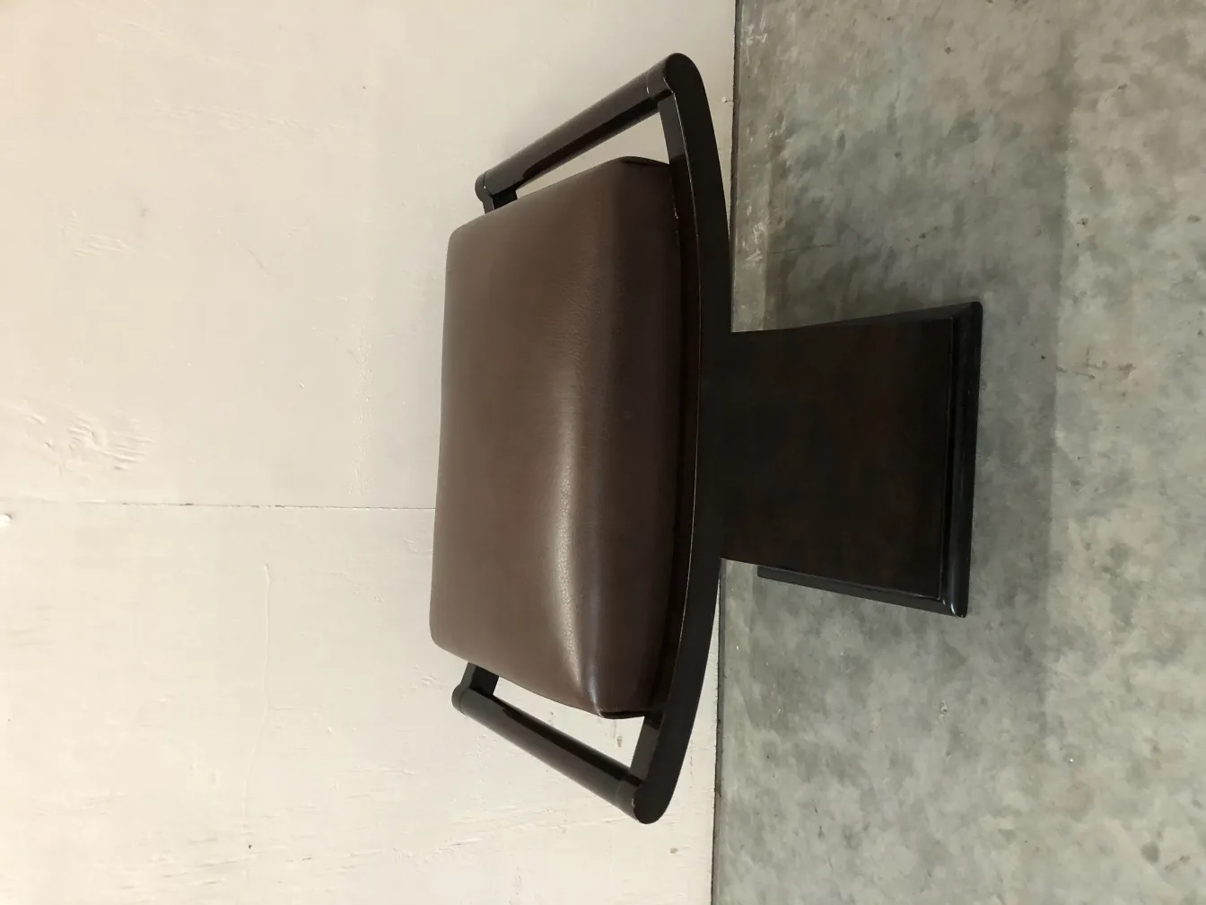 antique stool with elegant shape and brown padding in a neutral setting