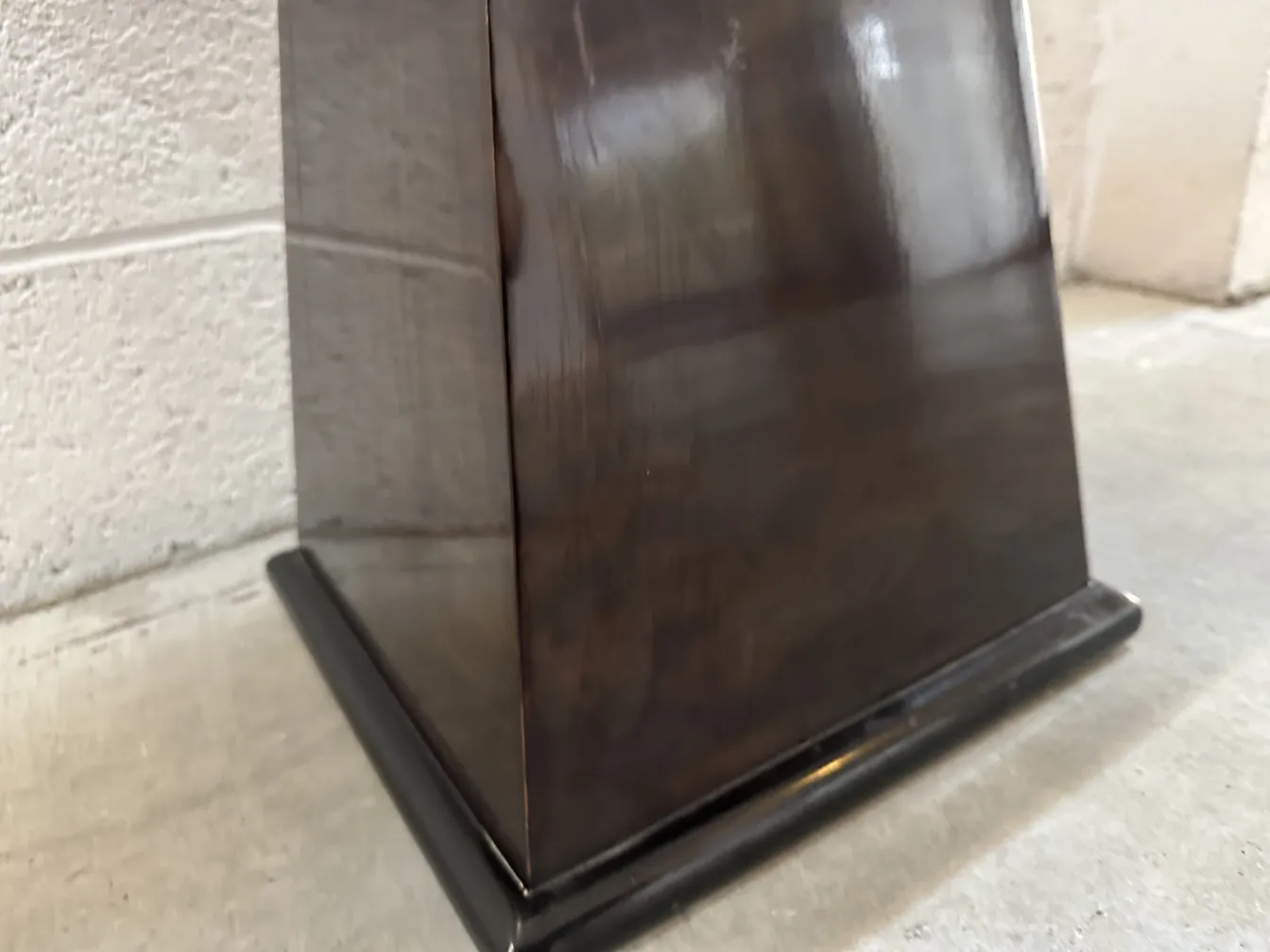Side view of an antique stool with a black base in a rustic setting.