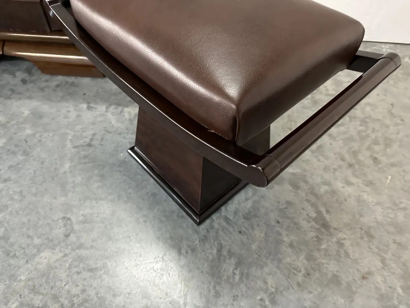 tabouret ancien marron avec accoudoirs dans un cadre neutre