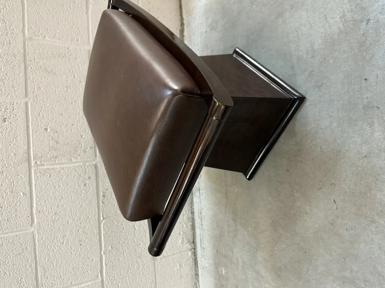 Antique stool with dark seat in neutral setting.