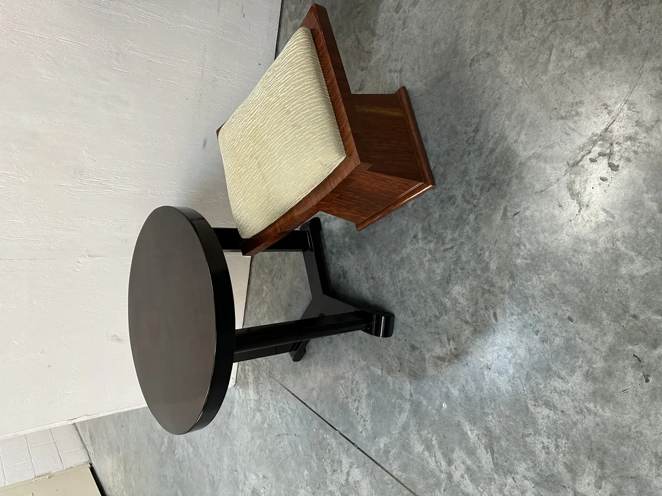 Antiker Hocker mit weichem Sitz neben einem runden Tisch