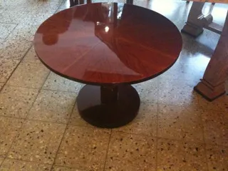 Petite table ancienne ronde avec base circulaire, dans un cadre accueillant.