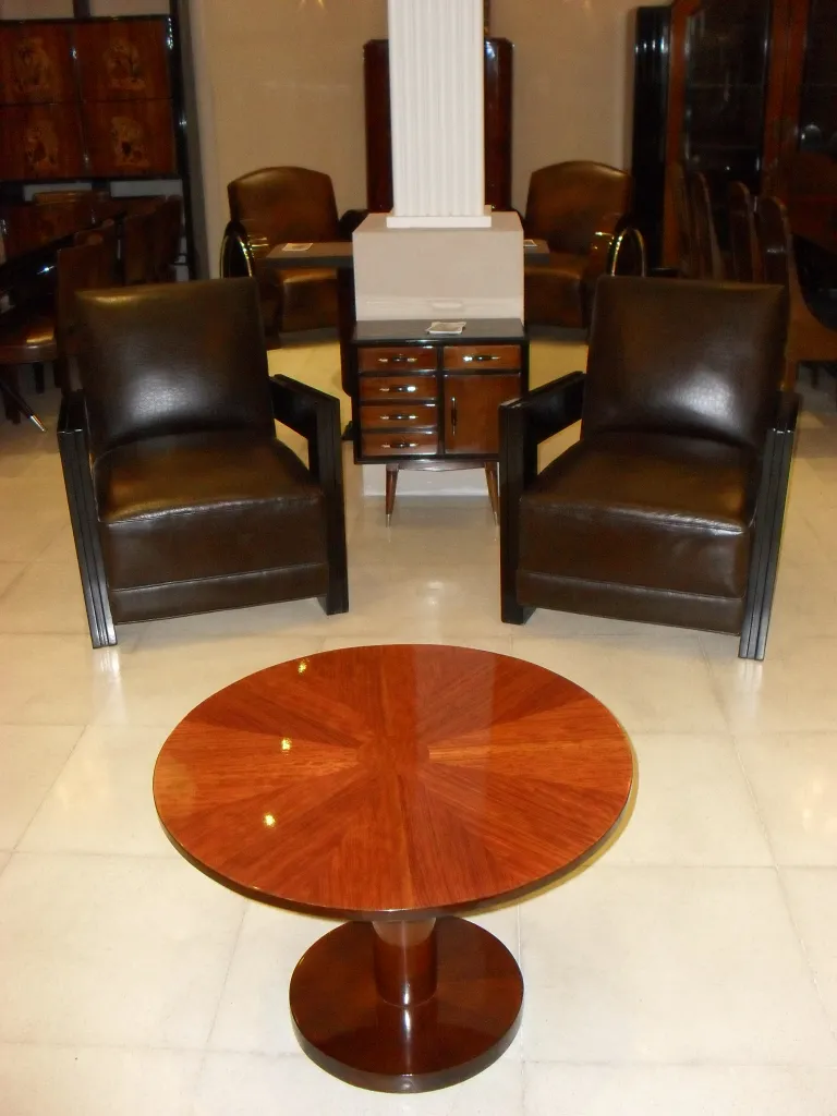 mesita antigua de forma redonda y patas cortas en salón elegante con sillones oscuros