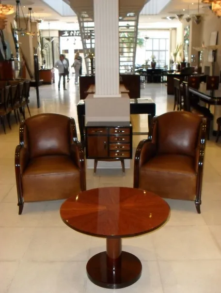petite table ancienne dans un salon avec des fauteuils marron