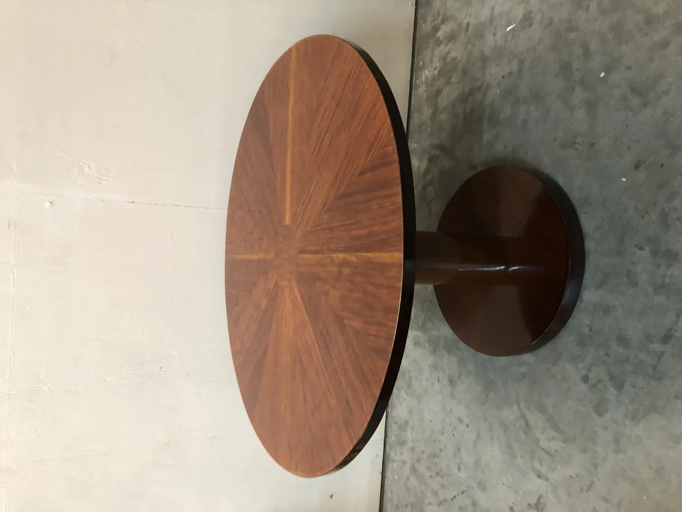 Tavolino antico rotondo con base solida in ambiente neutro.