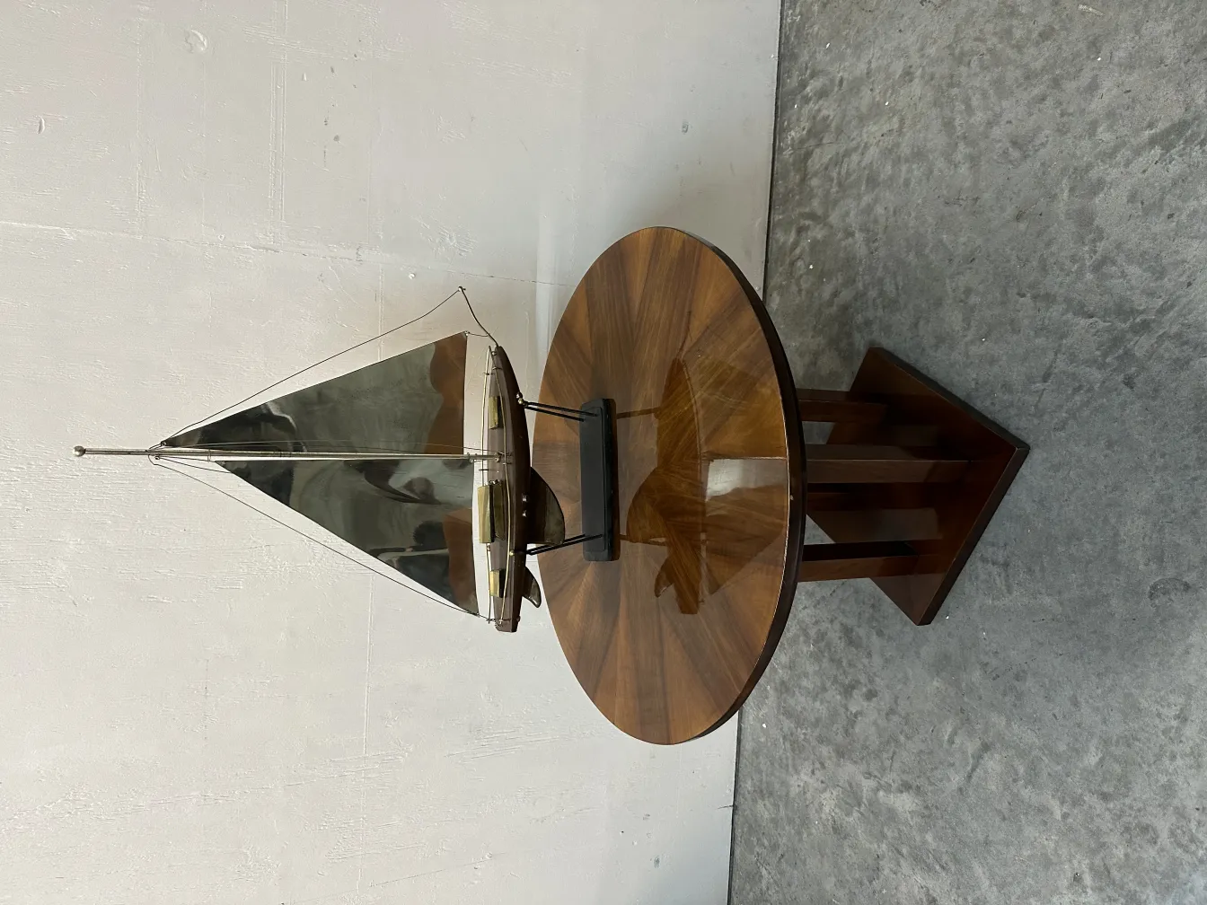 antique small table featuring a sailboat on top, set against a light surface and grey background