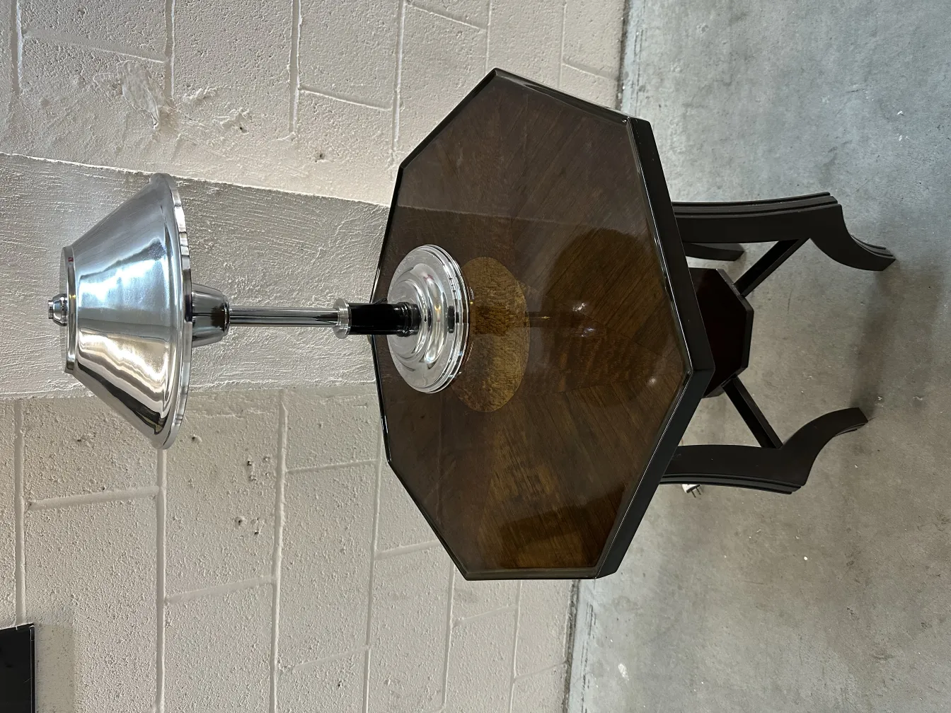 Petite table antique hexagonale avec lampe moderne, ambiance chaleureuse.