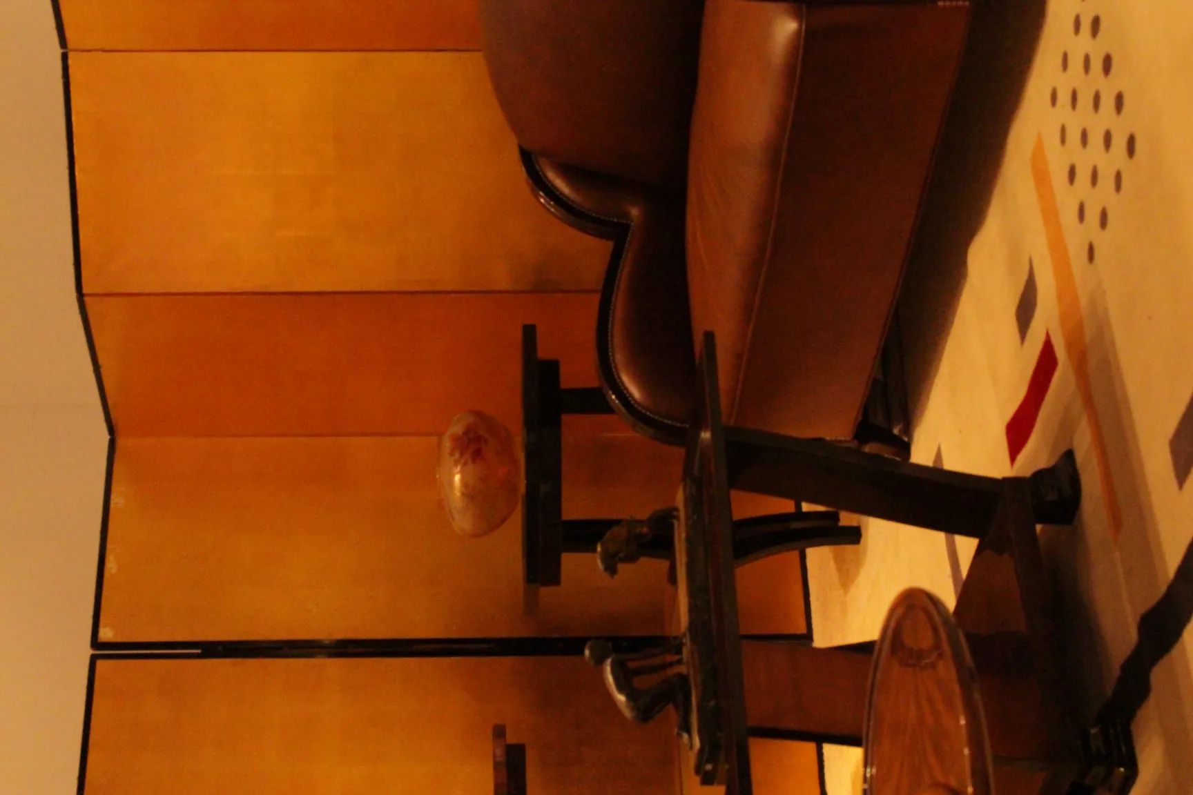 Ancienne petite table dans un cadre accueillant et élégant avec un canapé marron clair et des détails décoratifs sur le mur.