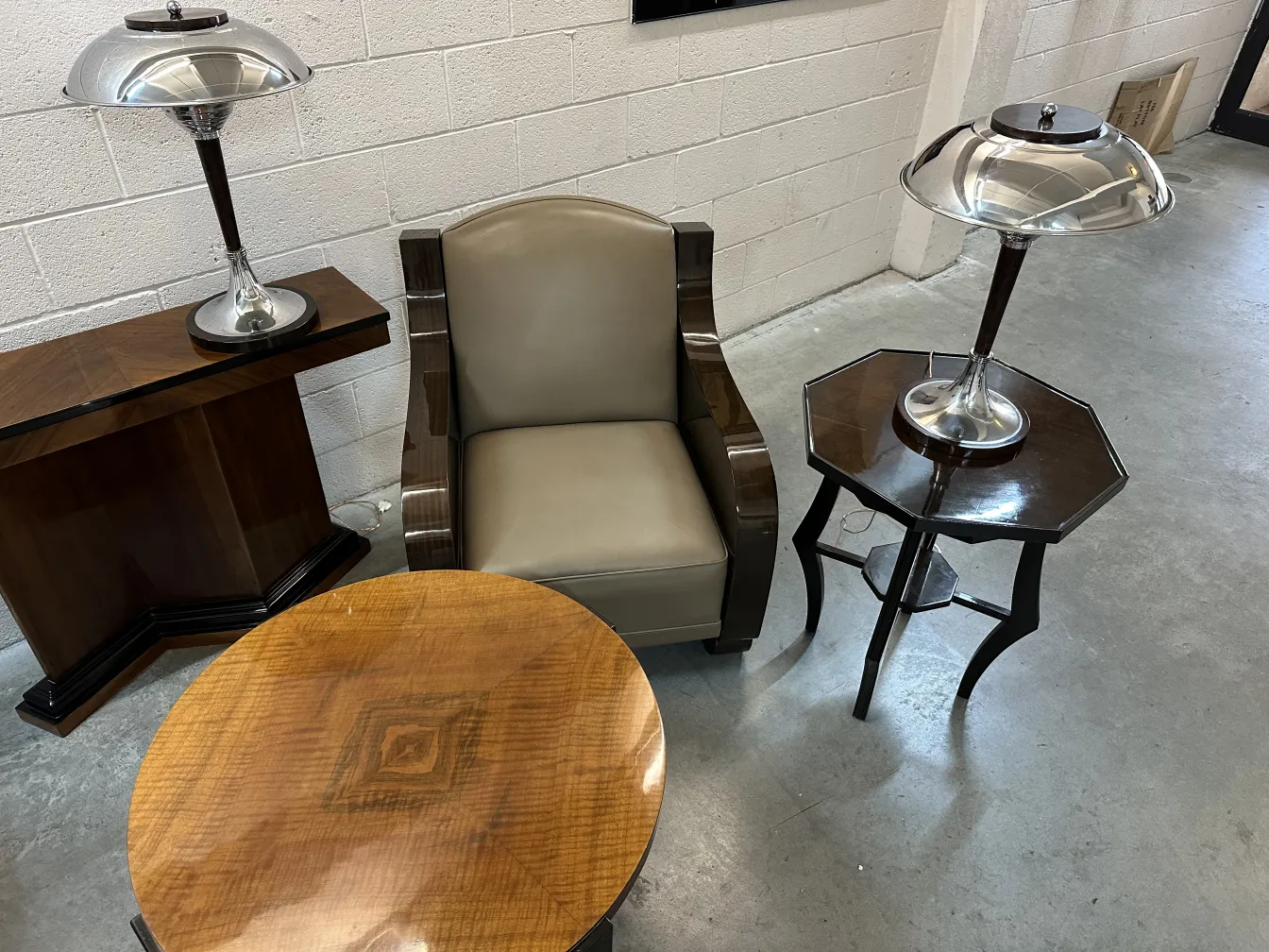 Antique round small table on gray floor, with lamp and armchair.