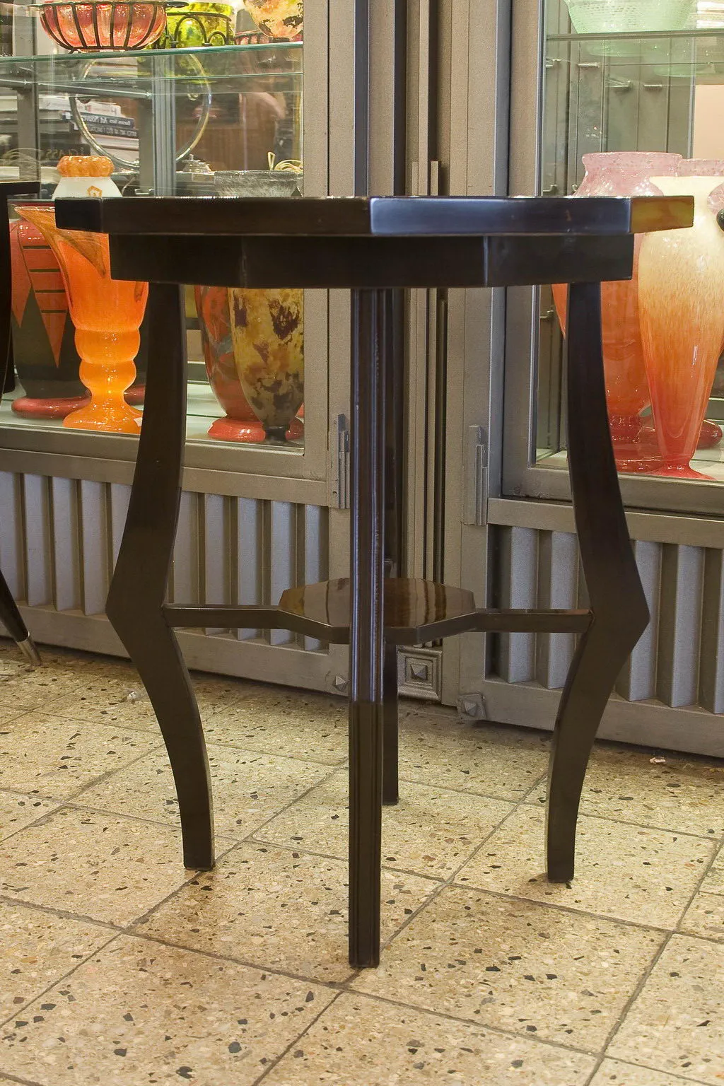 Tavolino antico con design elegante, vicino a vasi colorati.