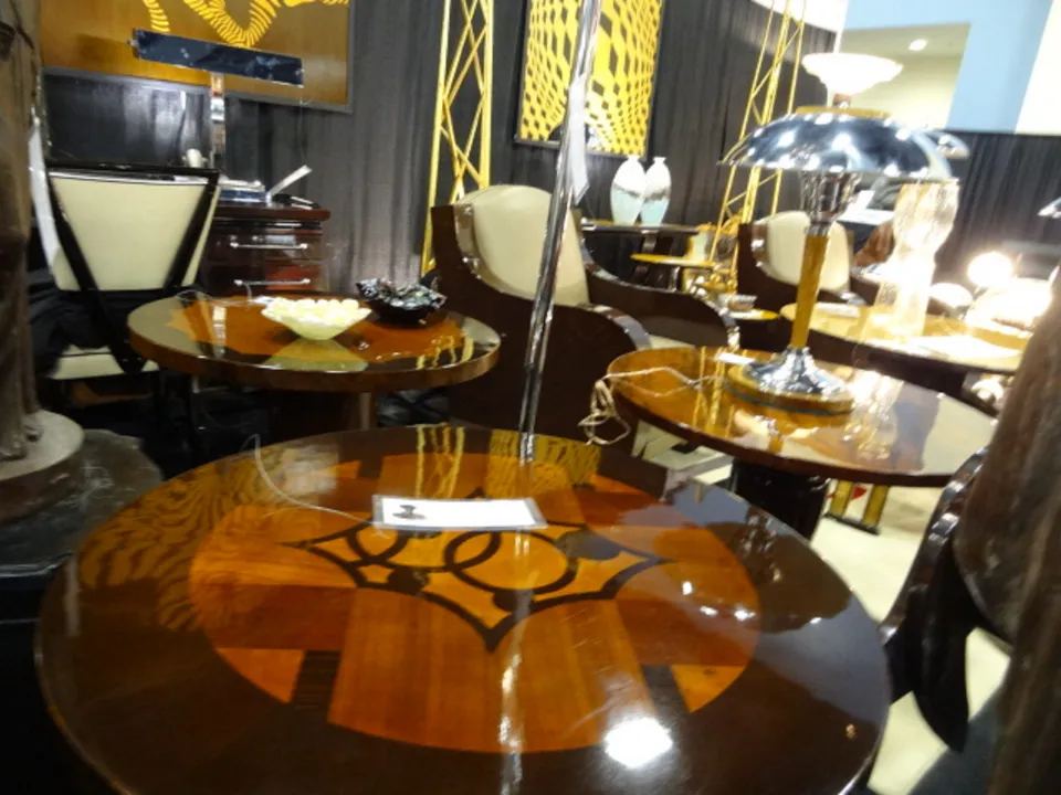 Tavolino antico con finitura lucida in un ambiente elegante con lampade e sedie.