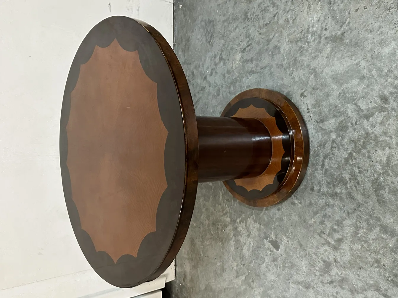 Antiker kleiner Tisch mit runder Basis in einer neutralen Umgebung.