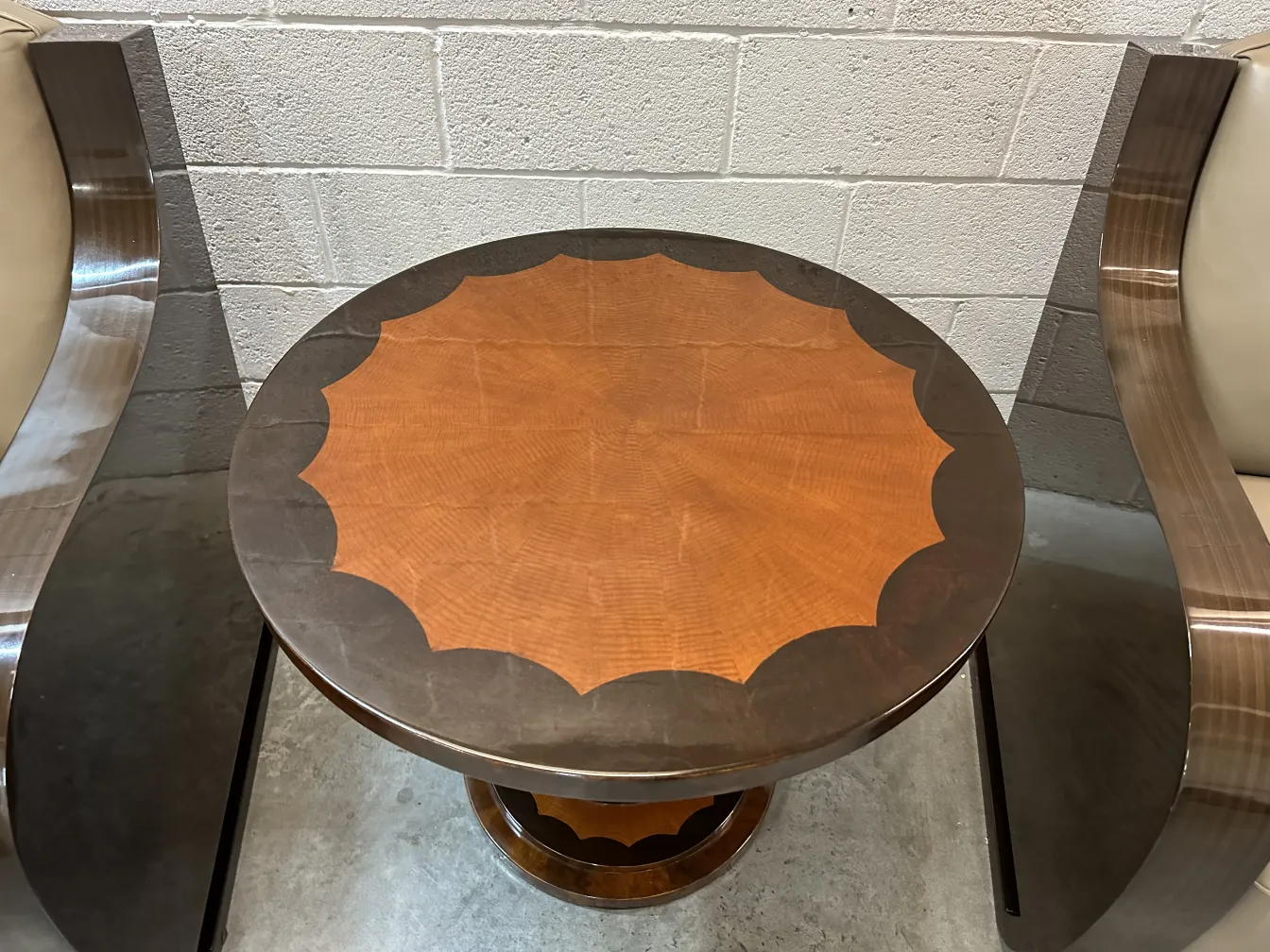 mesinha antiga redonda com base decorativa e detalhe no centro, cercada por cadeiras contemporâneas